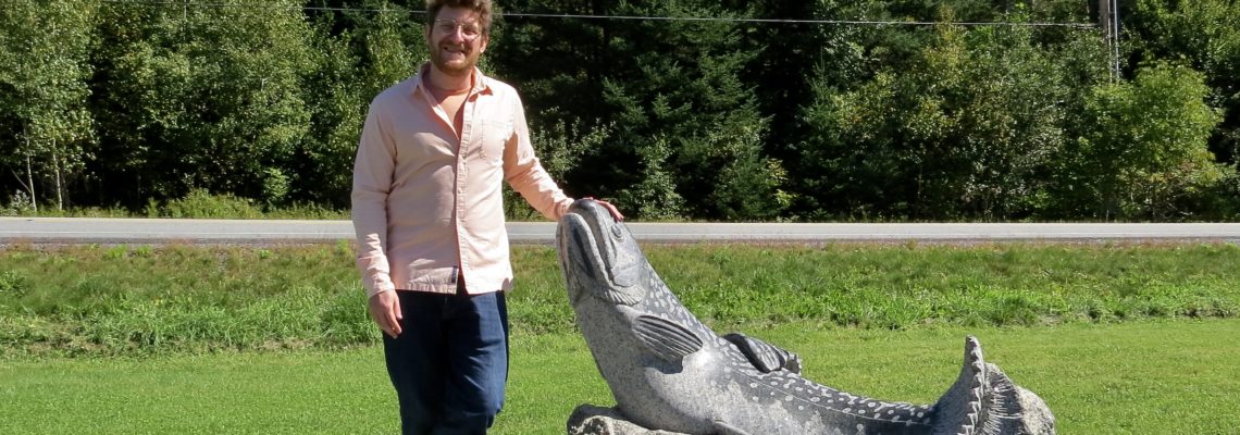 Sean Hunter Williams posing next to his sculpture of Brook Trout