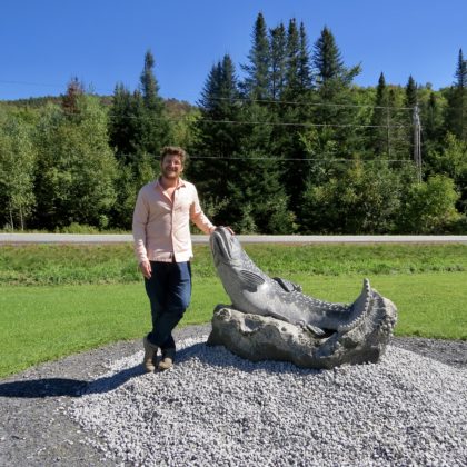 Sean  Hunter Williams, posing next to his sculpture of a Brook Trout