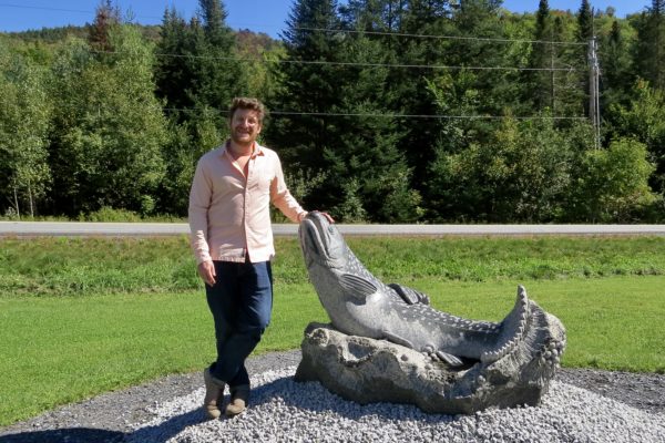 Sean Hunter Williams posing next to his sculpture of Brook Trout