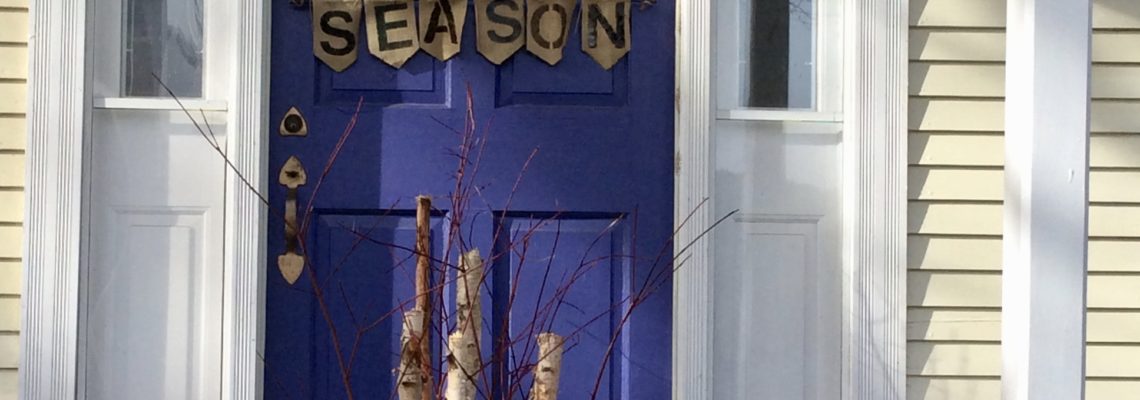 front door of inn with stick season sign, orange pot with sticks