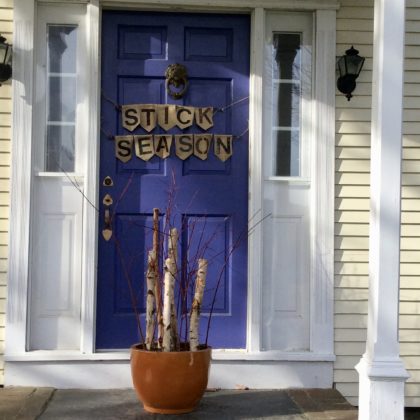 front door of inn with stick season sign, orange pot with sticks