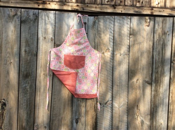 adult apron, upside down white birds on green& pink fabric with corner turned up showing coral reverse