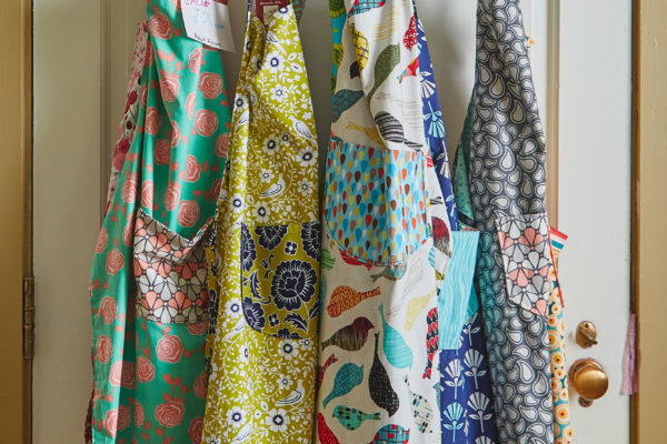 many colored aprons hanging on a hook