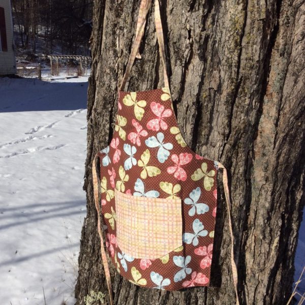 Childs apron with butterfly fabric, plaid pocket