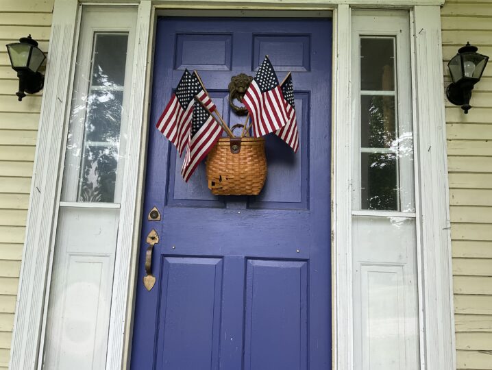 front, purple door of inn with basket of American flags
