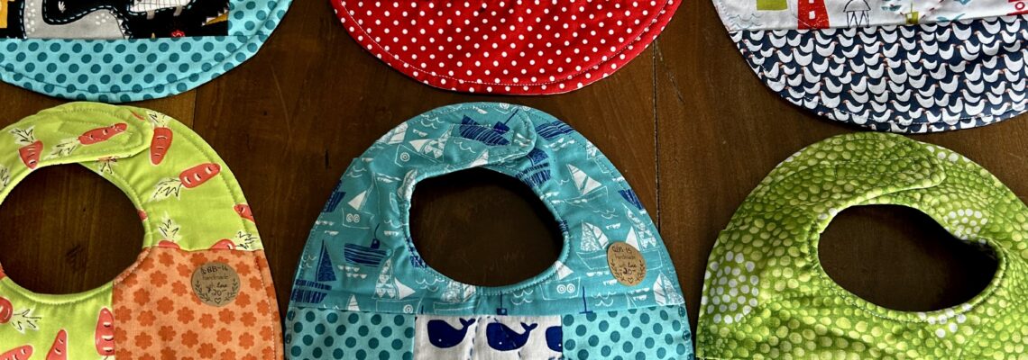 6 quilted baby bibs in various colors