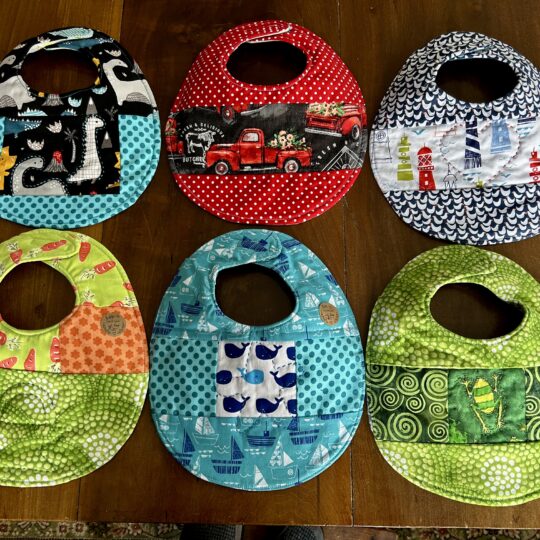 6 quilted baby bibs in various colors